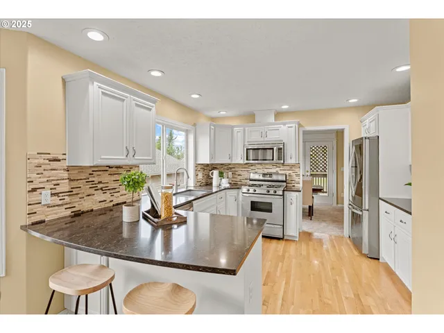 a kitchen with stainless steel appliances granite countertop a stove refrigerator sink and cabinets