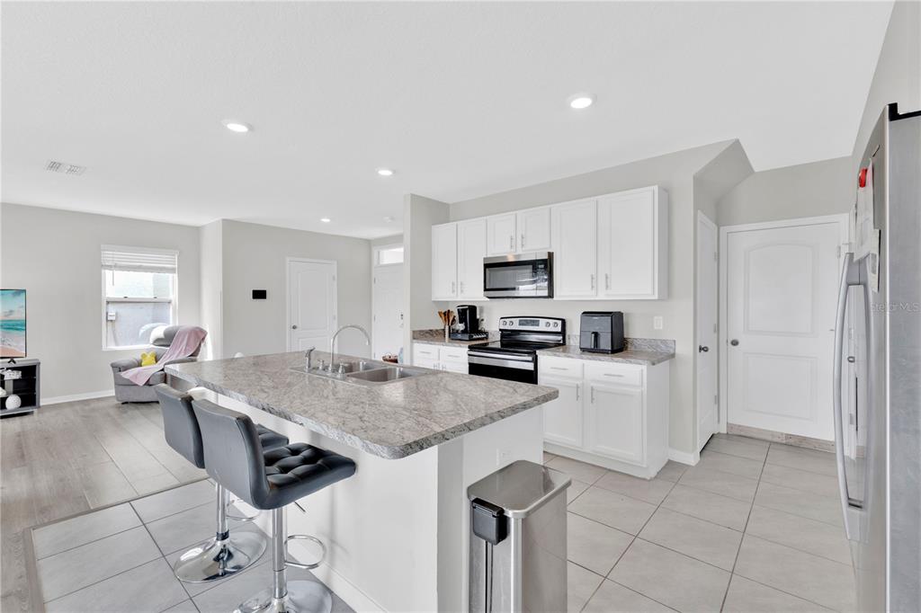 167 Eagleview Loop Davenport, FL 33837 - Photo 7 of 39 a kitchen with stainless steel appliances a stove a sink a microwave and cabinets