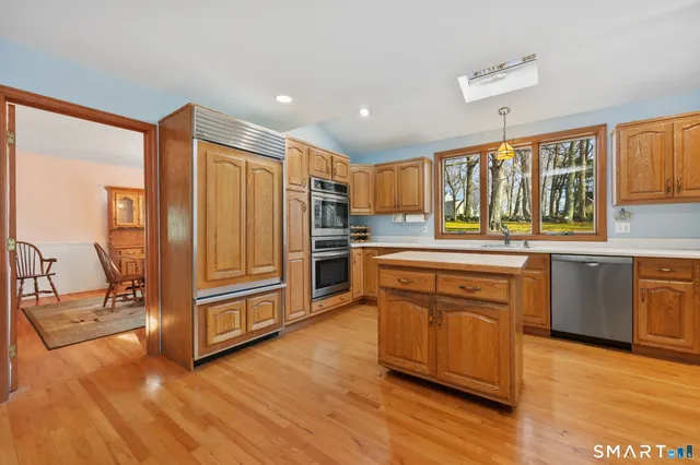 a kitchen with stainless steel appliances granite countertop a stove a sink dishwasher and a refrigerator with wooden floor