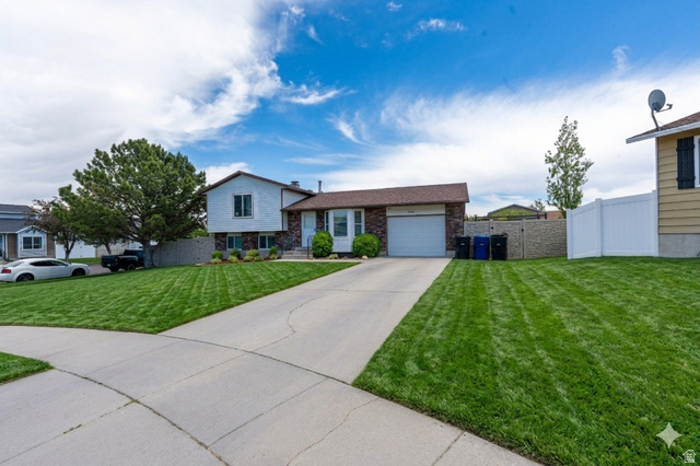 3689 Lasso Loop Circle Magna, UT 84044 - Photo 2 of 26 Ai enhanced front of this Split-level residence featuring a-car garage, concrete driveway, and a spacious front lawn with mature trees