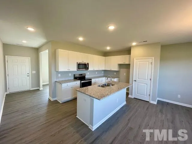 a large kitchen with a center island wooden floor stainless steel appliances and cabinets
