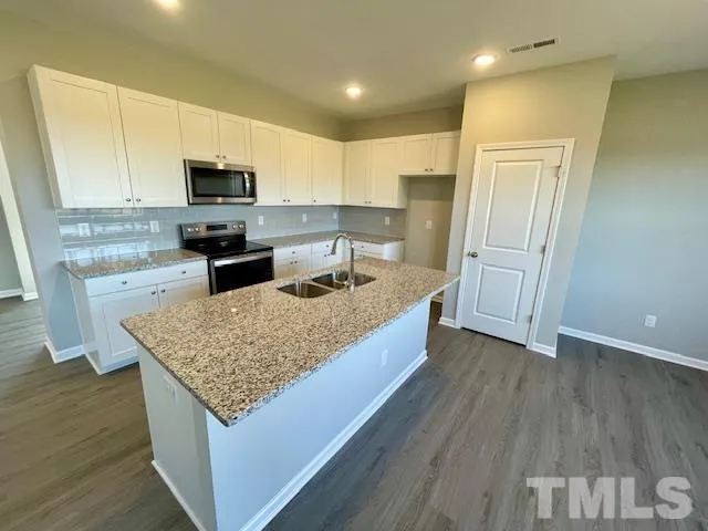 a kitchen with stainless steel appliances granite countertop a sink dishwasher stove and microwave with wooden floor
