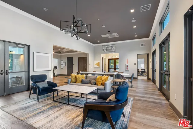 a living room with furniture a chandelier and a dining table with wooden floor