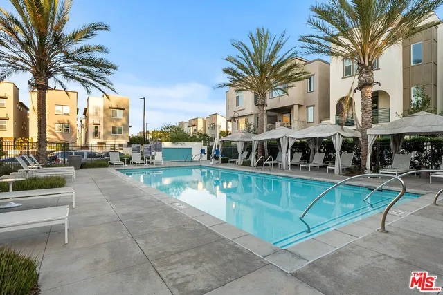 a view of a swimming pool with lawn chairs and plants