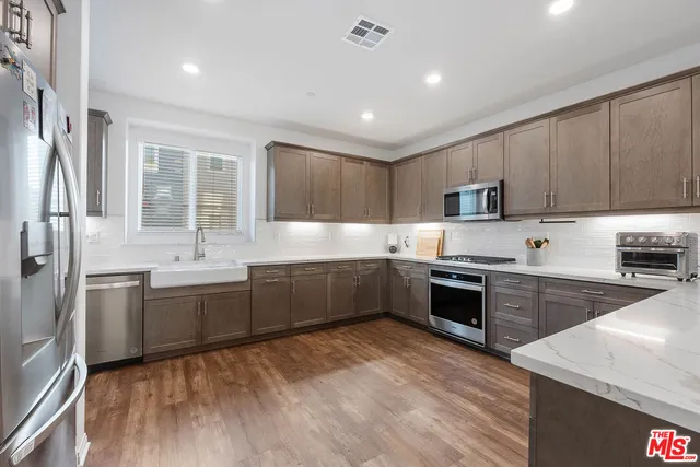 a large kitchen with stainless steel appliances granite countertop a stove sink and cabinets