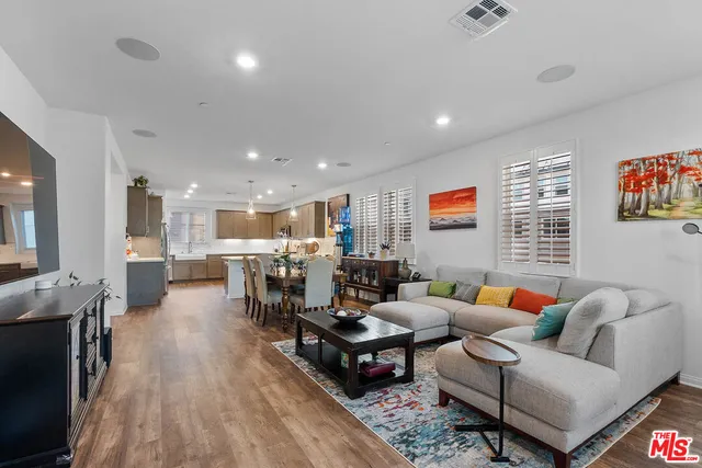 a living room with furniture kitchen view and a wooden floor