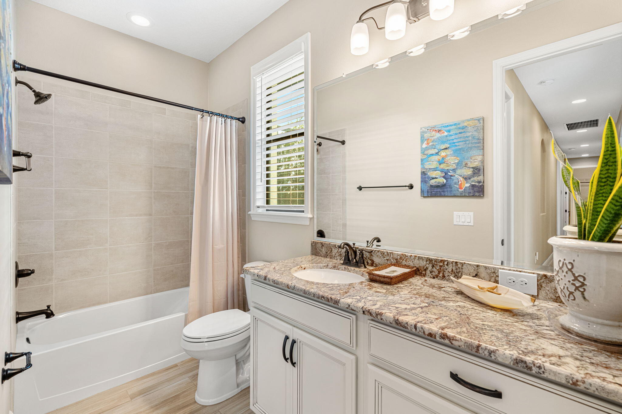 2911 Addison Drive Melbourne, FL 32940 - Photo 16 of 36 a bathroom with a granite countertop sink a toilet a mirror a vanity a bathtub and shower