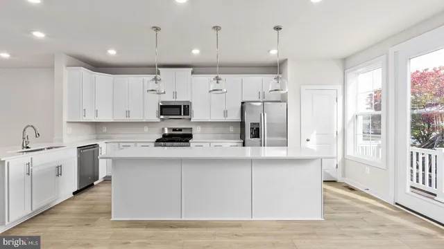 a kitchen with stainless steel appliances granite countertop a sink a stove a refrigerator cabinets and a window