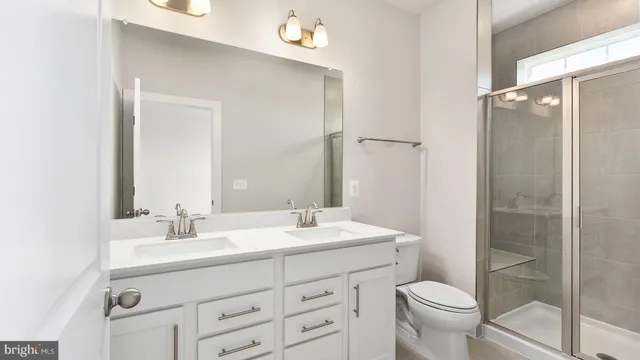 a bathroom with a sink a toilet a mirror and shower