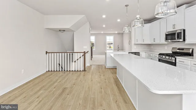 a large white kitchen with stainless steel appliances granite countertop a stove a sink dishwasher and a microwave with wooden floor