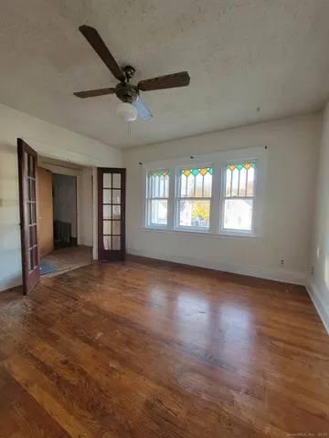 a view of an empty room with a window and wooden floor