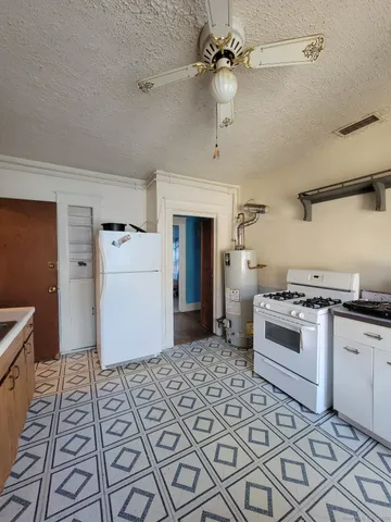a kitchen with granite countertop a stove a sink and a refrigerator