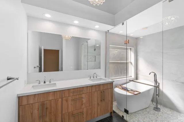a bathroom with a tub double sink window and mirror