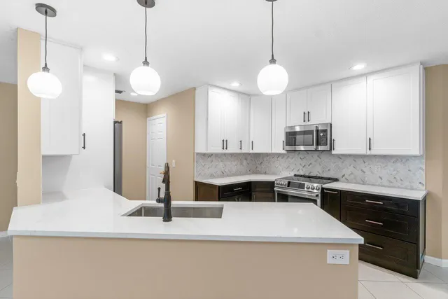 a kitchen with kitchen island granite countertop a stove a sink and a counter top space