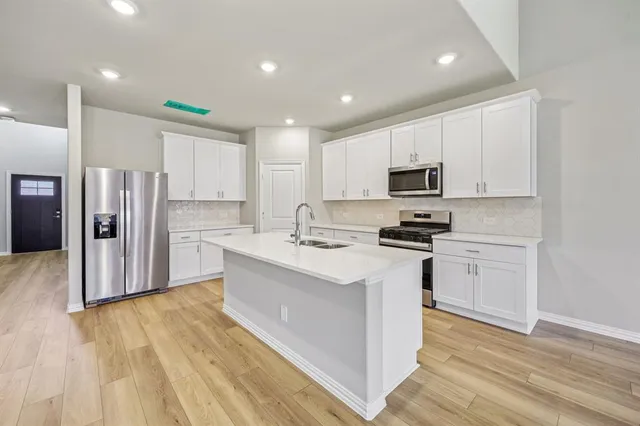 a kitchen with stainless steel appliances granite countertop a refrigerator stove top oven and sink