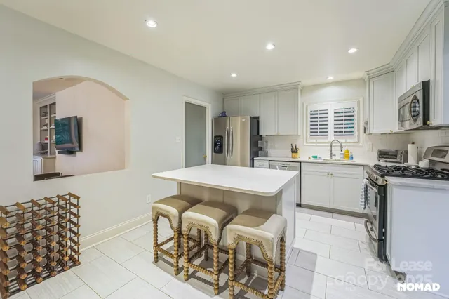 a kitchen with stainless steel appliances granite countertop a sink a stove a refrigerator a microwave a counter top and cabinets