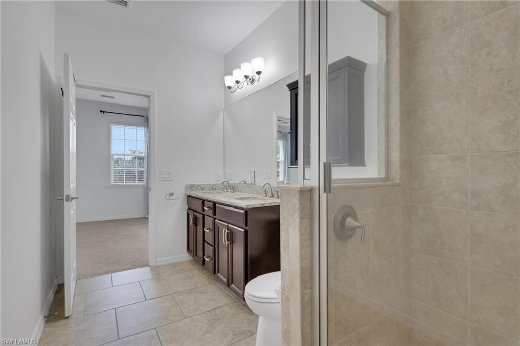 18320 Creekside Preserve Loop, Unit 201 Fort Myers, FL 33908 - Photo 16 of 27 Bathroom with double vanity, light tile patterned floors, and a shower stall
