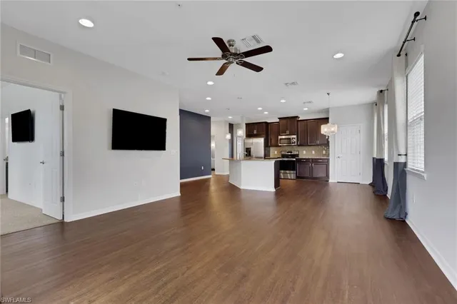 a view of an empty room with kitchen appliances and a ceiling fan