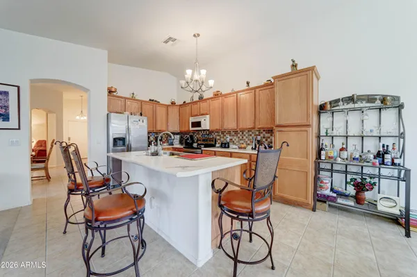 a kitchen with stainless steel appliances kitchen island granite countertop a dining table chairs and a refrigerator