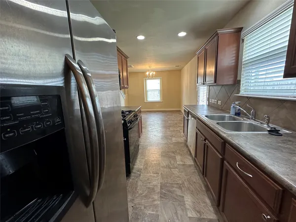 a kitchen with stainless steel appliances granite countertop a refrigerator a sink a stove and oven