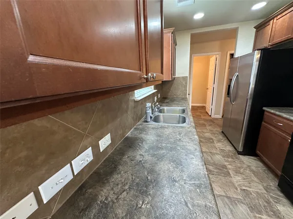 a view of a refrigerator in kitchen and an empty room