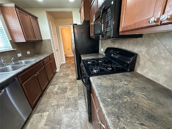 a kitchen with stainless steel appliances granite countertop a stove a sink and a microwave