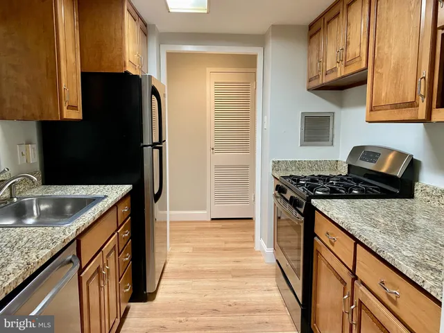 a kitchen with granite countertop a sink stove and refrigerator
