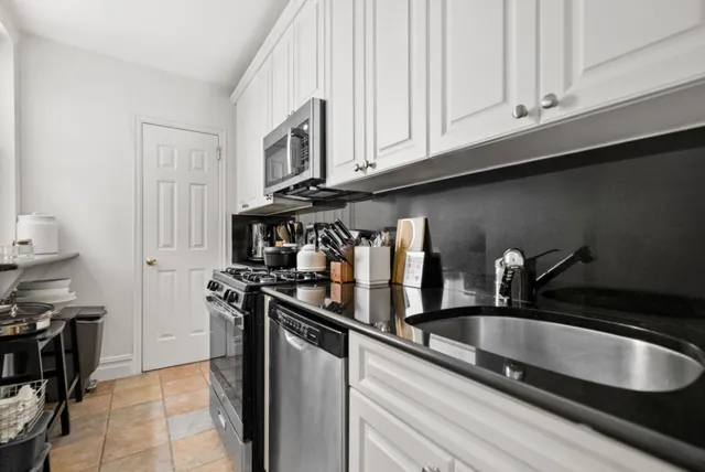 a kitchen with stainless steel appliances granite countertop a sink a stove and a refrigerator with wooden cabinets