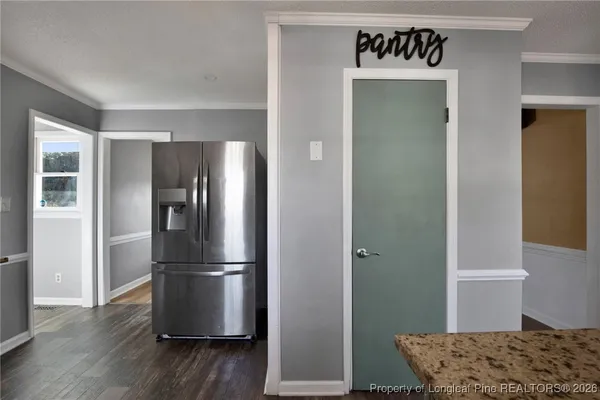 a walk in closet with wooden floor and a bathroom