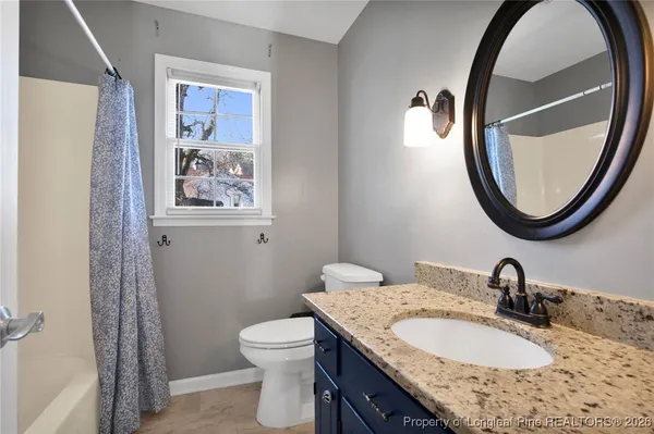 a bathroom with a granite countertop toilet a sink and a mirror