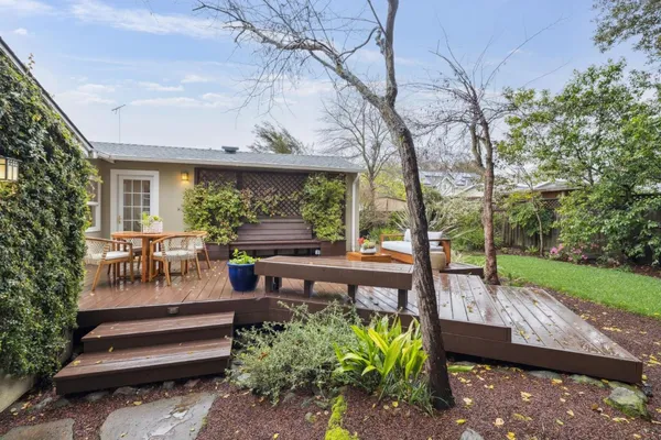 a view of a patio with table and chairs potted plants and large tree