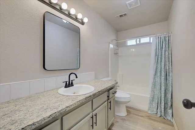 a bathroom with a granite countertop sink a toilet and a mirror