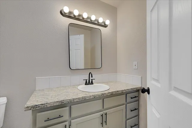 a bathroom with a granite countertop sink and a mirror