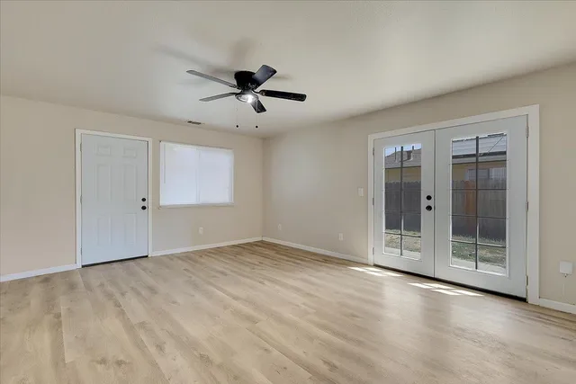 a view of empty room with wooden floor and fan