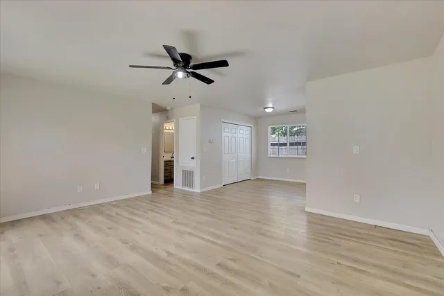 a view of empty room with wooden floor and ceiling fan