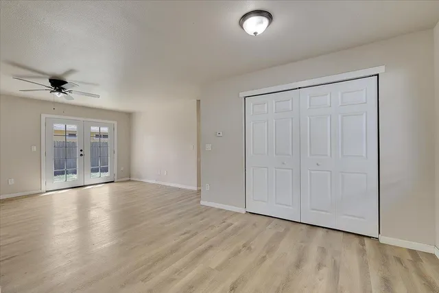an empty room with wooden floor and a ceiling fan