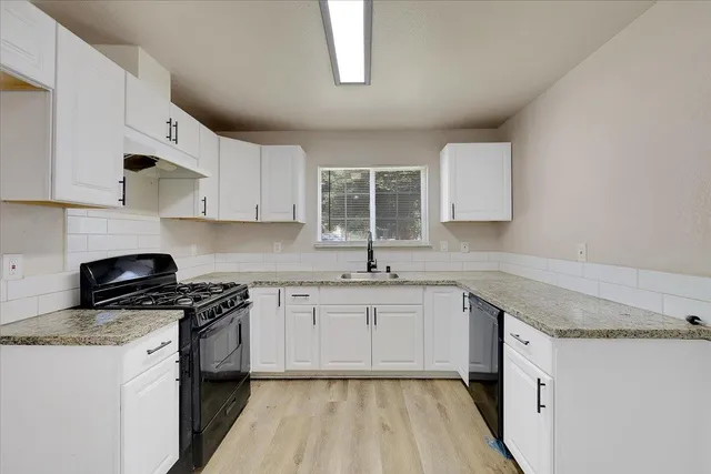 a kitchen with granite countertop cabinets stainless steel appliances a sink and a window