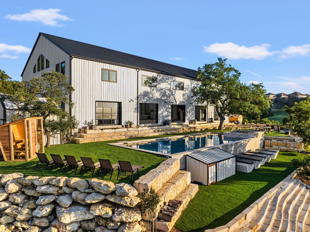 Resort-style pool and terraced outdoor living areas behind the barn-style main residence.