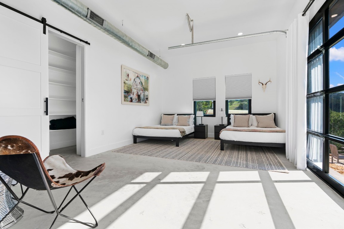 12701 Trails End Road Leander, TX 78641 - Photo 15 of 18 Guest bedroom featuring two beds, concrete floors, large windows for natural light and adjacent closet/storage area.