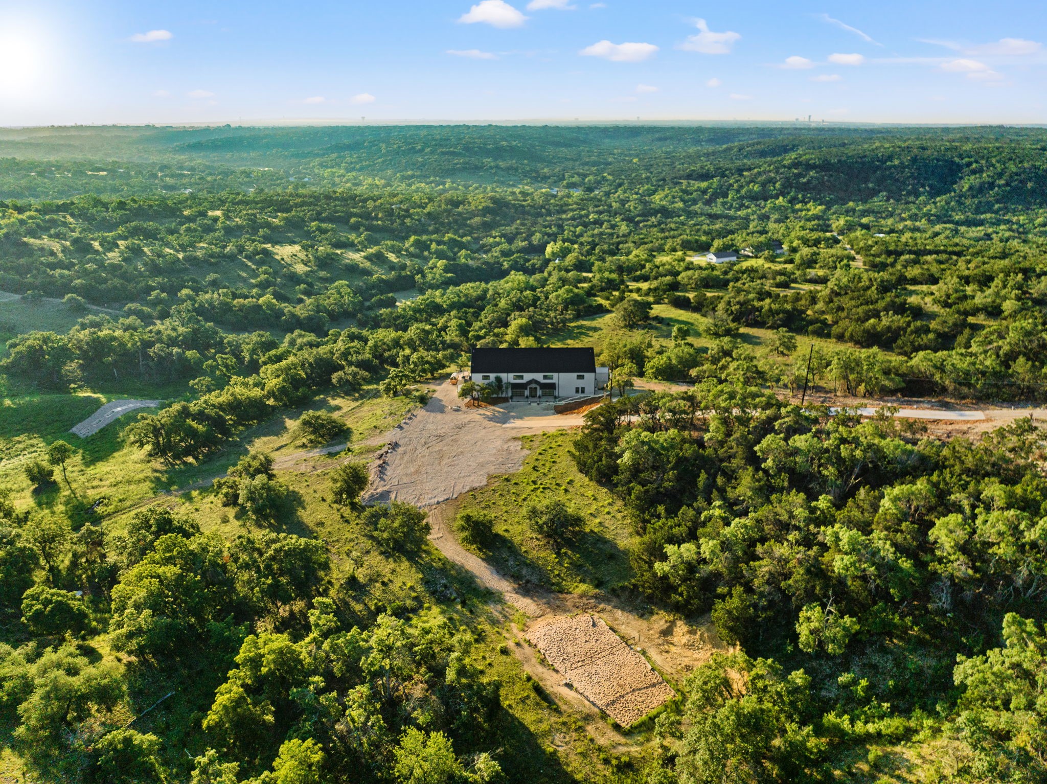 12701 Trails End Road Cedar Park, TX 78613 - Photo 2 of 18 Wide aerial view showing the main residence, sand volleyball court, drive access and surrounding Hill Country terrain.