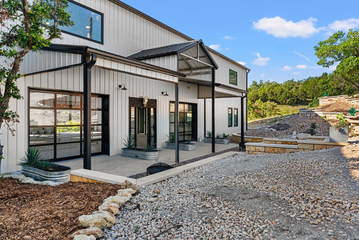12701 Trails End Road Leander, TX 78641 - Photo 5 of 18 Covered front porch and entry of the barn-style main residence with metal roof, concrete patio and landscaped approach.