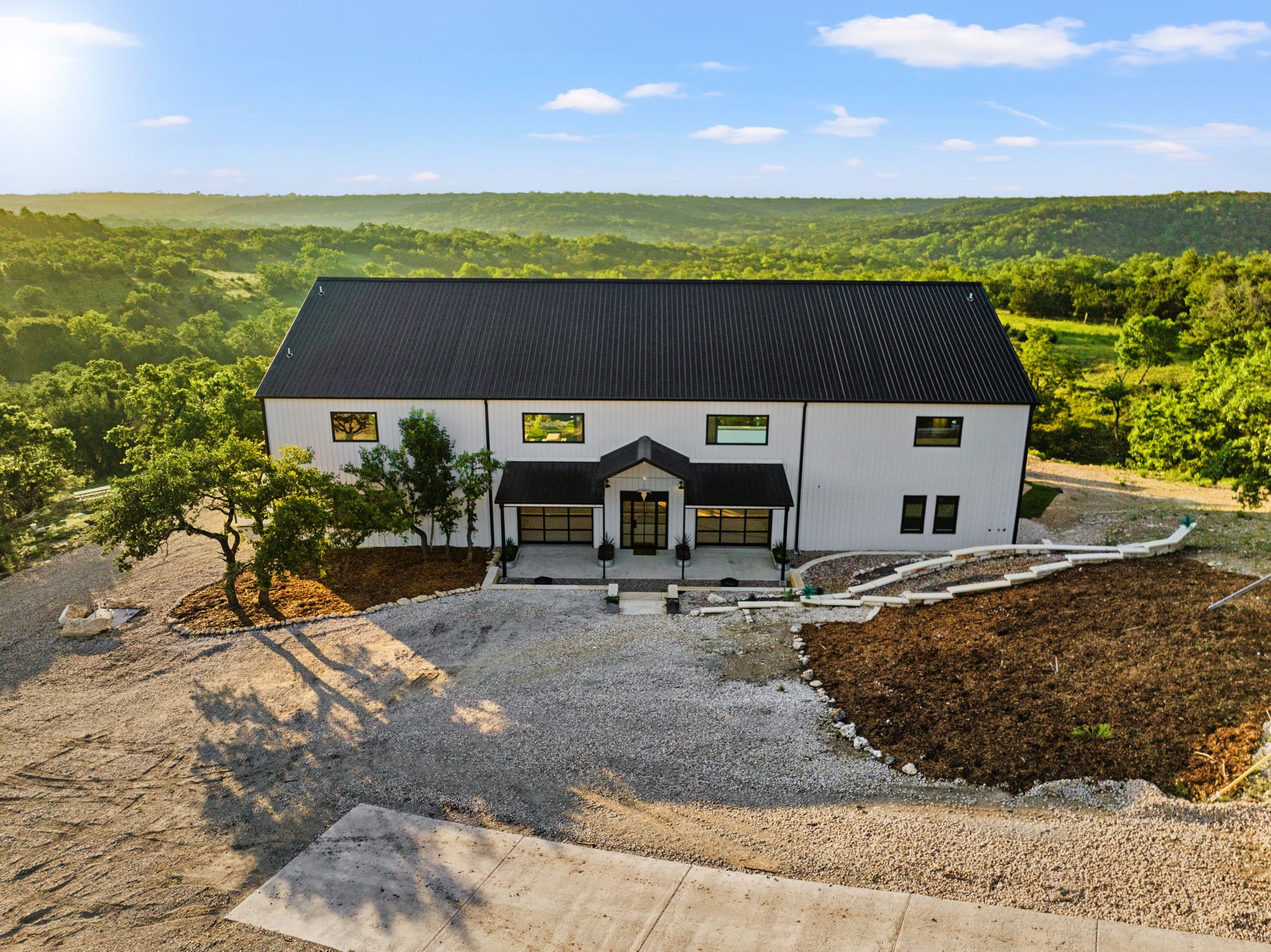 12701 Trails End Road Cedar Park, TX 78613 - Photo 6 of 18 Aerial view of the barn-style main residence showing the front entry, drive approach and surrounding Hill Country landscape.