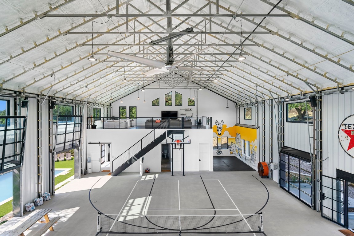 12701 Trails End Road Leander, TX 78641 - Photo 7 of 18 Interior of the indoor recreation building featuring a full-size basketball court, open mezzanine level and large overhead doors for indoor-outdoor use.