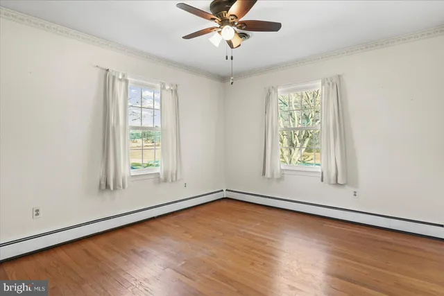 an empty room with wooden floor fan and windows