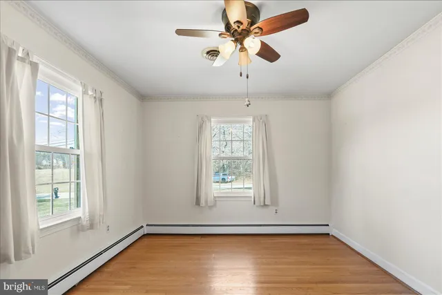 an empty room with wooden floor fan and windows