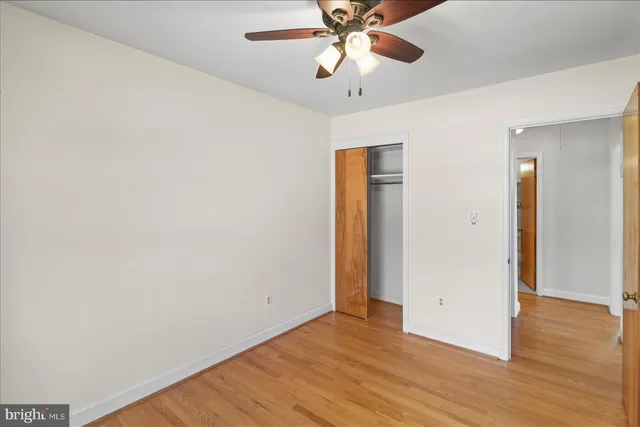 an empty room with wooden floor and fan
