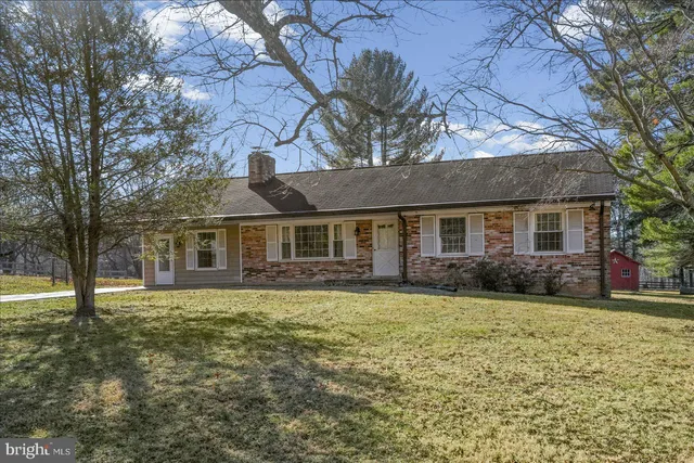 a front view of a house with a garden and trees