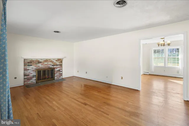 an empty room with wooden floor fireplace and windows