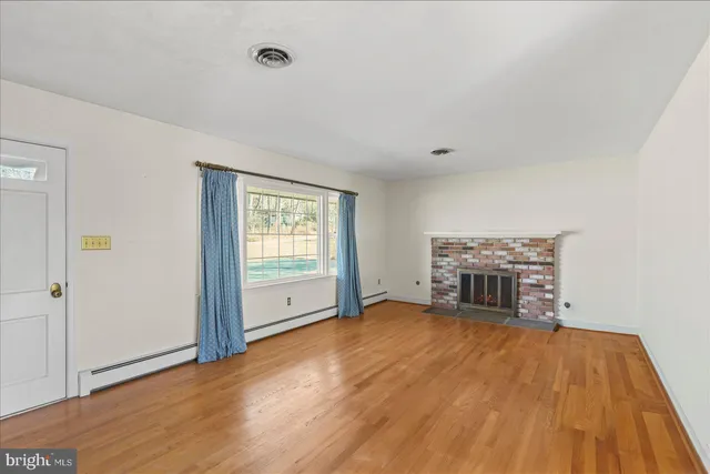 a view of empty room with wooden floor and fireplace