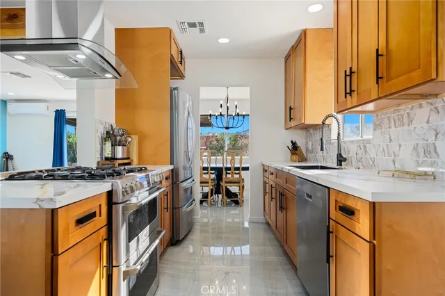 a kitchen with stainless steel appliances granite countertop a stove a sink and a refrigerator